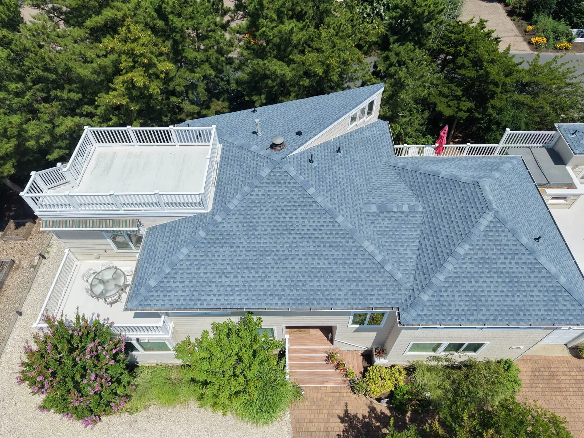 Aerial drone view of a completed blue gray asphalt shingle roof replacement on a coastal New Jersey home