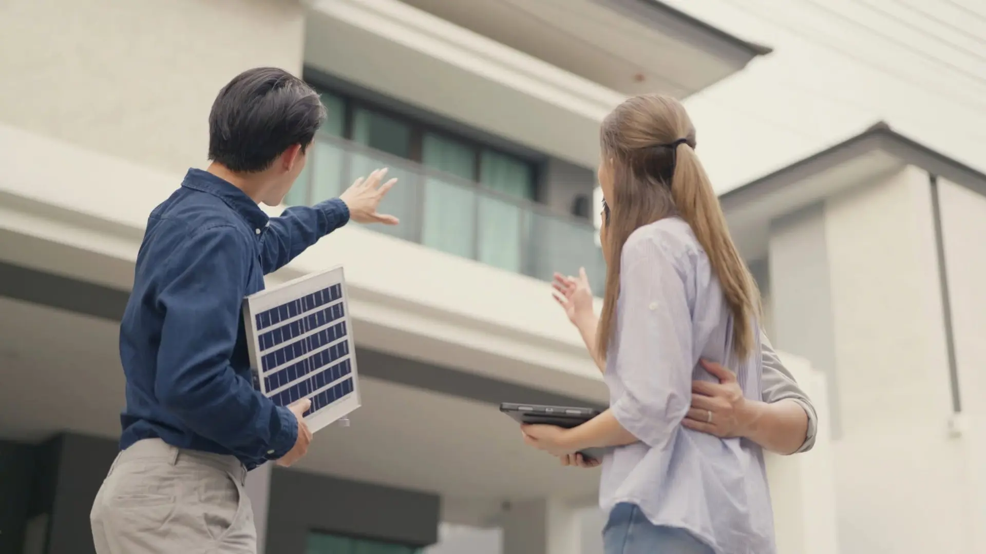 Solar consultant showing a homeowner a solar panel sample outside a New Jersey home