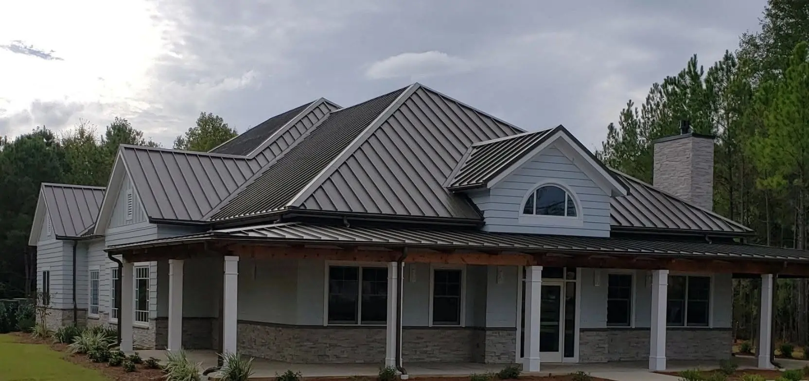 Dark bronze standing seam metal roof on a custom home with a wraparound porch in Ocean County, NJ
